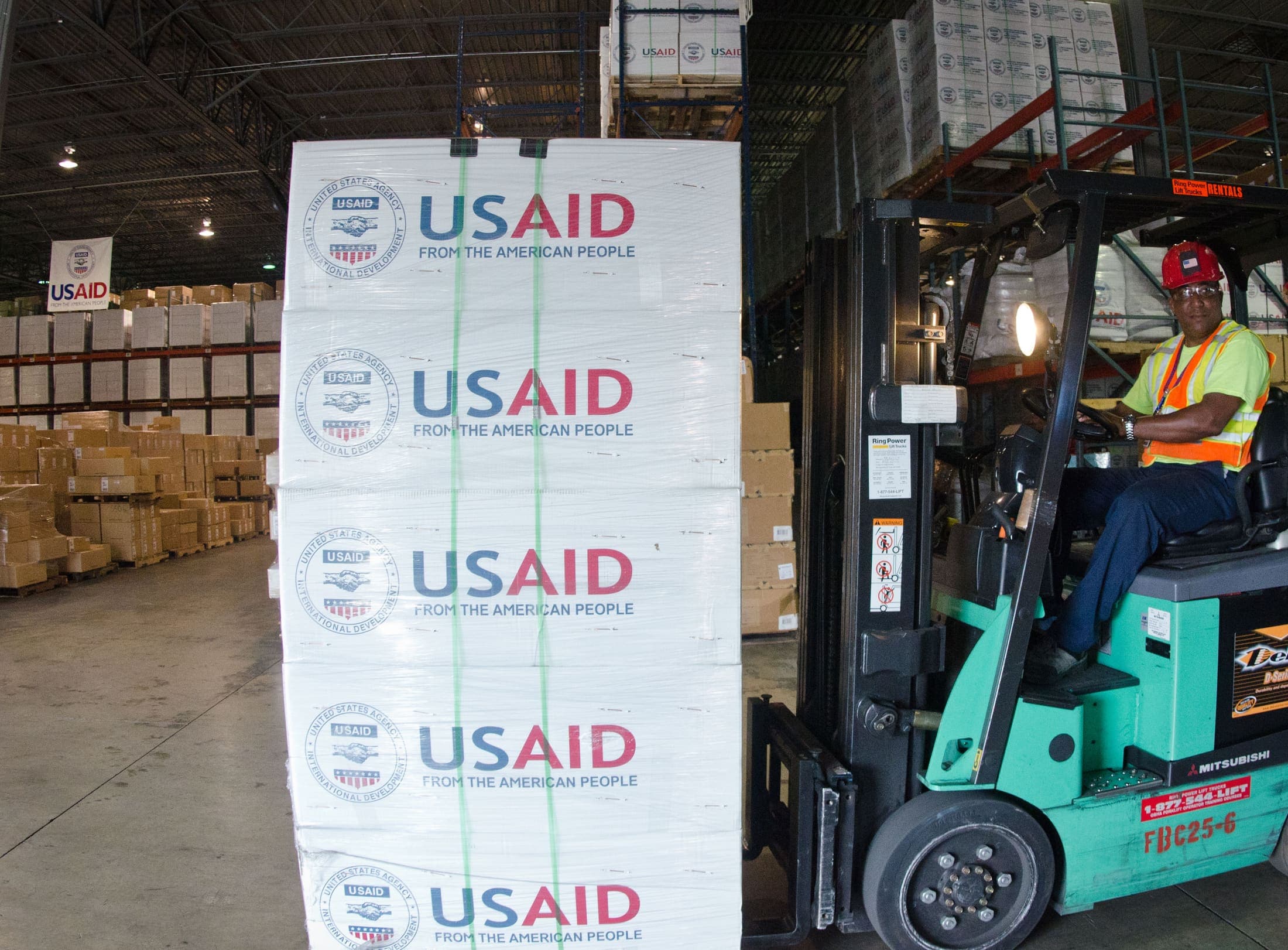 Warehouse workers moving palletised goods with forklifts